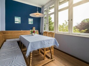 A room with a wooden bench, a table with a tablecloth, and a hanging light fixture. - Holiday Apartments Proll (Heringsdorf)
