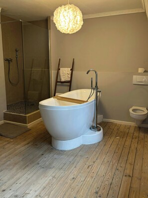 Ein modernes Badezimmer mit einer freistehenden Badewanne, einer Duschkabine und einer Toilette.