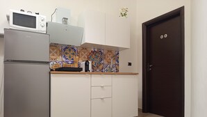Et køkken med køleskab, mikrobølgeovn og et mønstret backsplash.