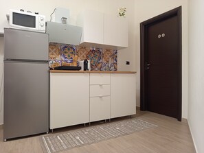 A kitchen with a refrigerator, microwave, and a patterned backsplash. - Holiday Home 'La Bouganville' with Wi-Fi (Trinitapoli)