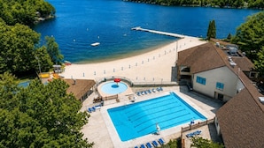 Un resort con piscina, zona de playa y vistas a un lago.