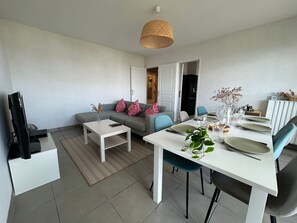 Un salon moderne avec un canapé, une table basse et une table à manger, le tout disposé pour un repas.