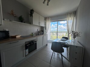 A modern kitchen with a dining area, a view of the city, and a balcony. - Bright 3-Bedroom Apartment with Balconies, Open Views, and Wi-Fi (Vannes)