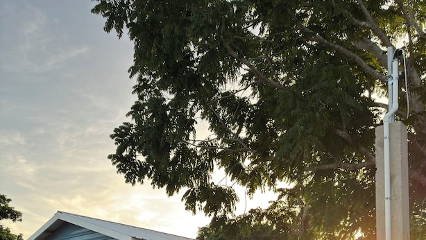 A small, single-story house with a porch, a staircase leading to the entrance, and a clear view of the sunset in the background.