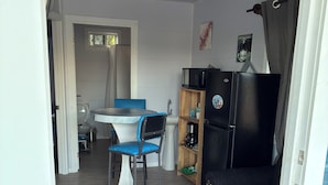 A compact living space with a kitchenette, a dining area with a table and chairs, and a sofa.