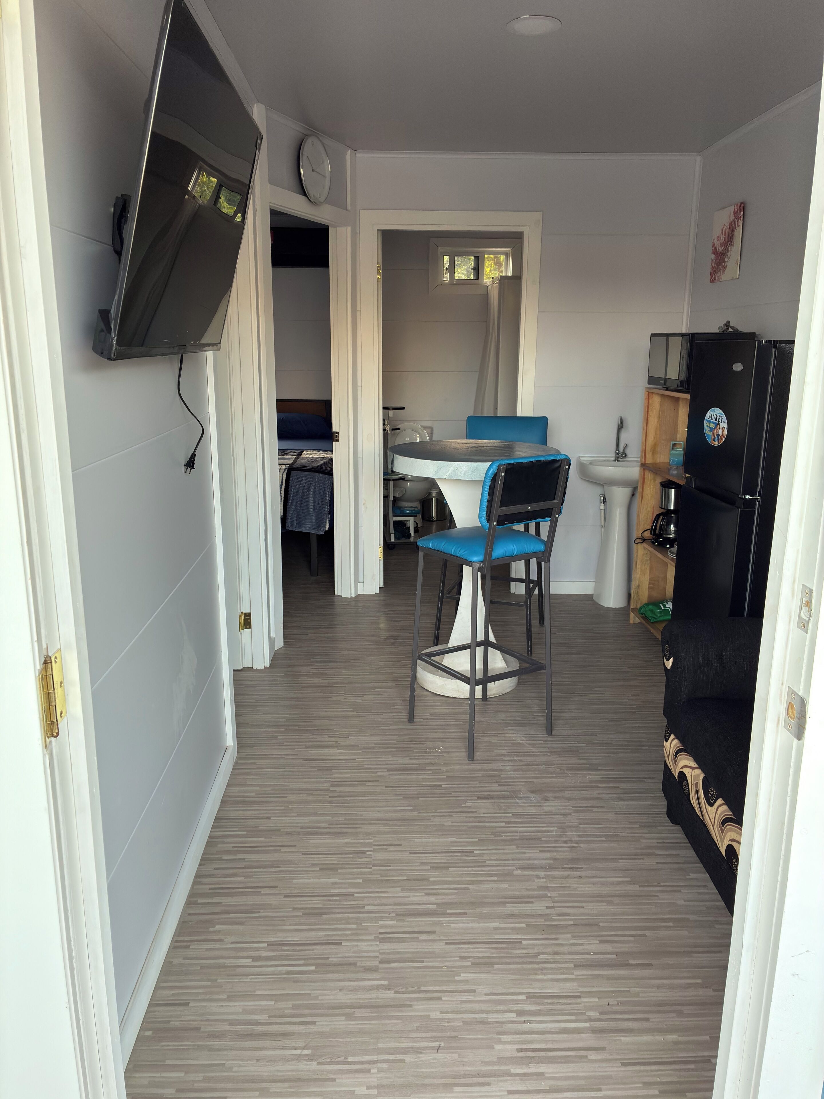 Un espace de vie compact comprenant un coin cuisine, un coin repas avec une table et des chaises, et un canapé.