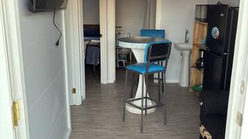 Un espace de vie compact comprenant un coin cuisine, un coin repas avec une table et des chaises, et un canapé.