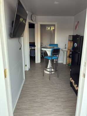 A compact living space with a kitchenette, a dining area with a table and chairs, and a sofa.