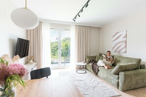 Ein modernes Wohnzimmer mit Sofa, Couchtisch, Fernseher und Blick ins Freie.