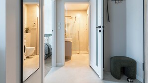 Ett modernt badrum med en dusch som är avskärmad med glasväggar och en toalett som syns genom en öppen dörr.