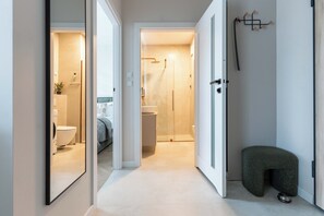 Ein modernes Badezimmer mit einer gläsernen Duschkabine und Toilette, die durch eine geöffnete Tür sichtbar ist.