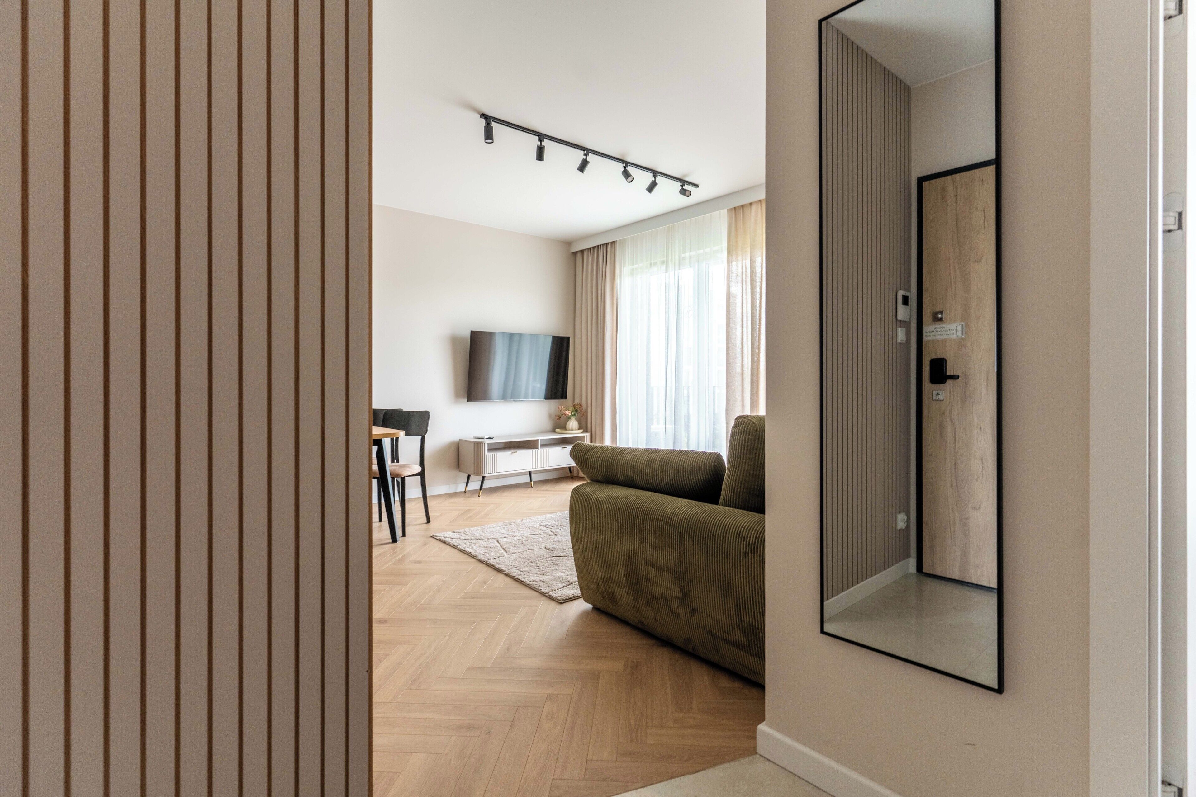 Una sala de estar moderna con un sofá, un televisor y piso de madera.