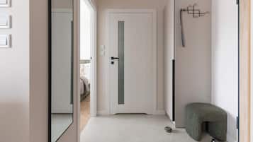 Un pasillo con una puerta blanca, un perchero y una cama para mascotas.
