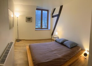Ein Schlafzimmer mit einem Bett, einem Fenster, einer Stehlampe und einer Heizung.
