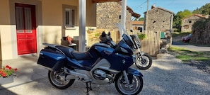 Una motocicleta estacionada frente a un edificio con puerta roja y paredes de piedra.