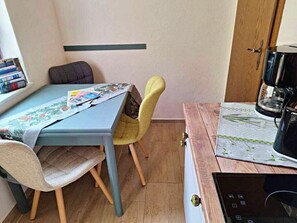 A compact kitchen with a table, chairs, a coffee machine, and a dishwasher. - Vacation at Umlauf (Heringsdorf)