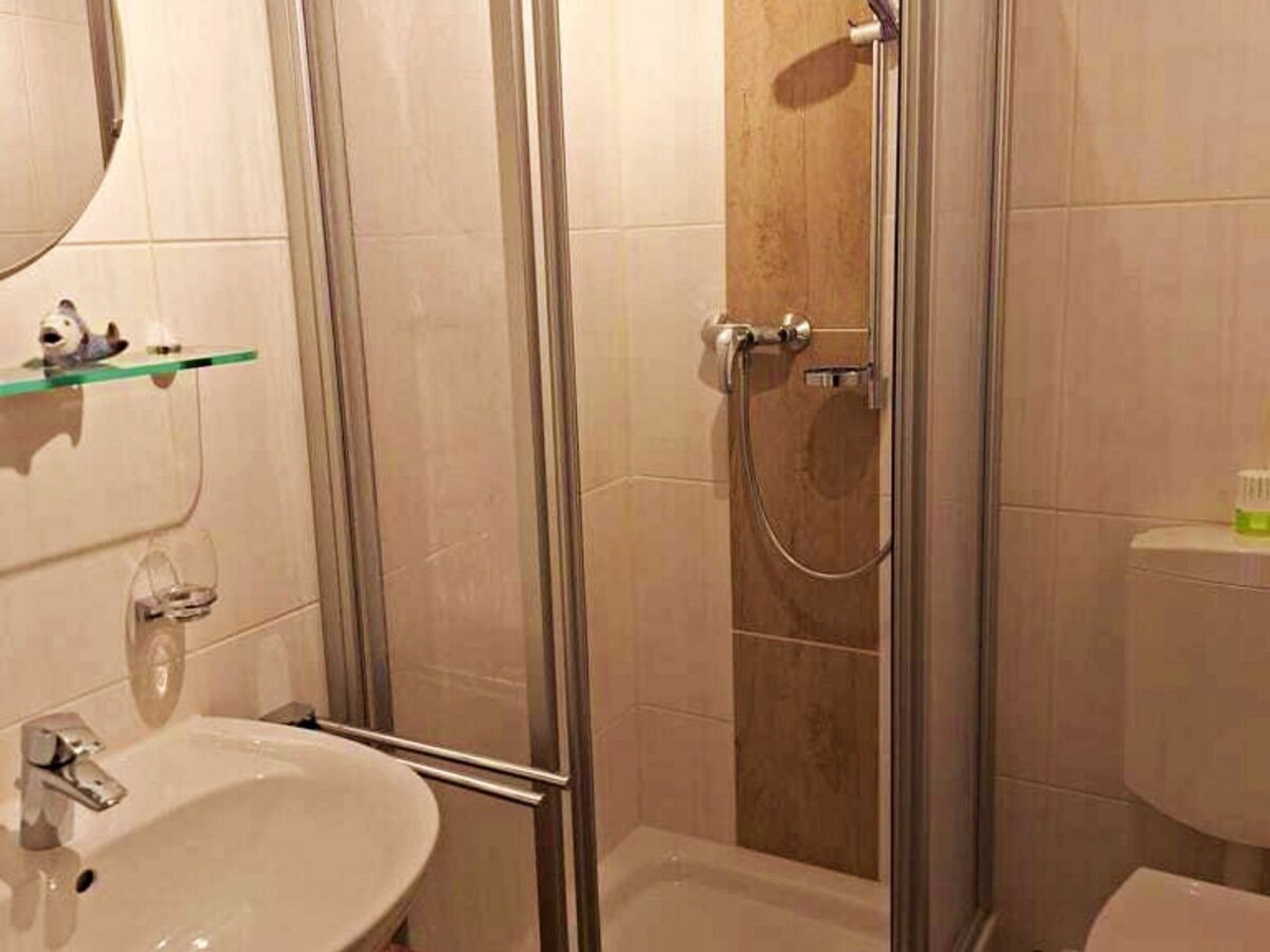 A bathroom with a glass-enclosed shower, a white sink, and a toilet.