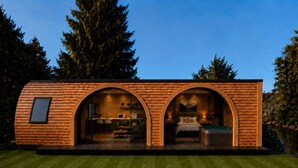 Una casa moderna e compatta con facciata in mattoni, due ingressi ad arco, un'area cucina visibile e una camera da letto con un letto e posti a sedere.