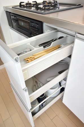 Een keuken met een inbouwfornuis en een lade-organizer met keukengerei.