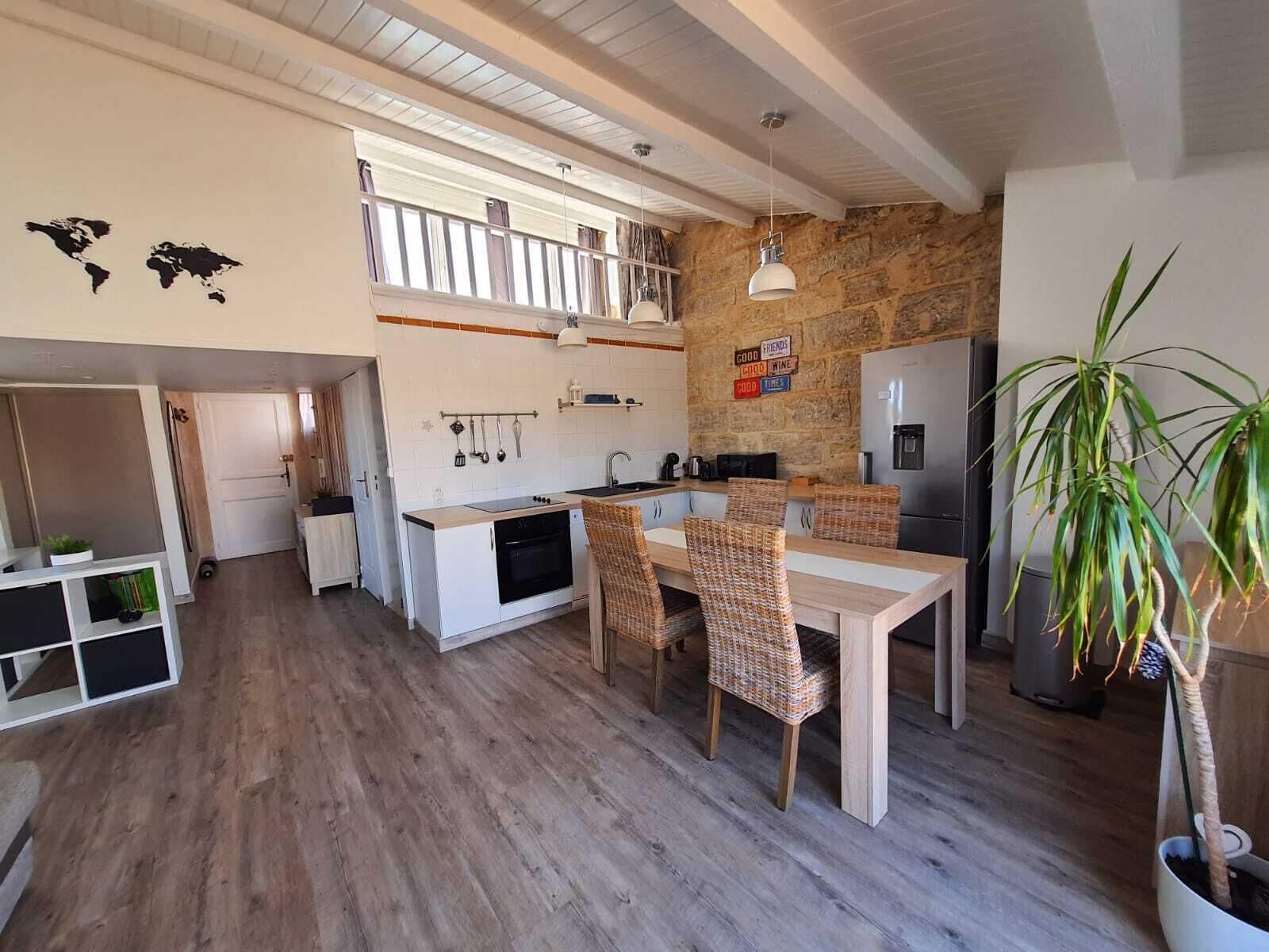 A compact kitchen with a dining area, wooden flooring, and a stone accent wall.