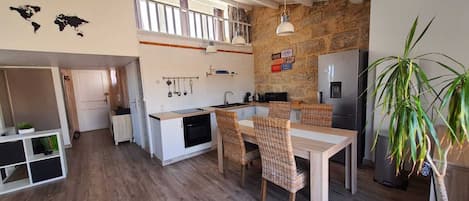 A compact kitchen with a dining area, wooden flooring, and a stone accent wall.
