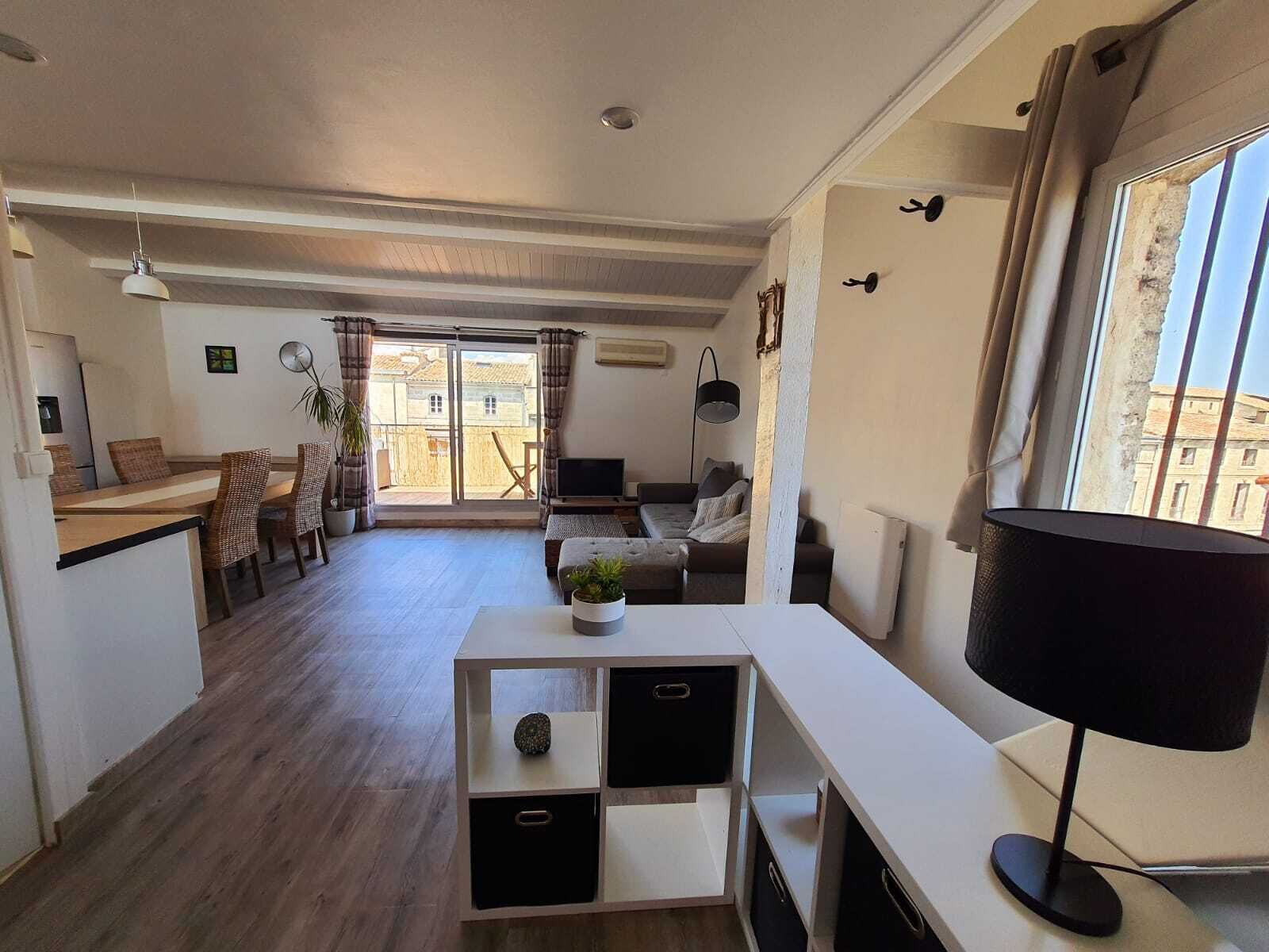 A modern living room with a sofa, a TV, and a dining area with chairs and a table.