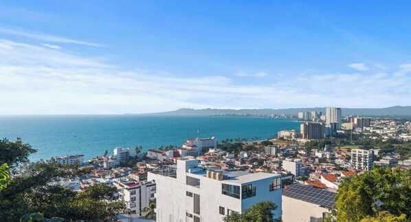 Paisagem costeira com edifícios, céu claro e vista para o mar.