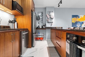 Eine moderne Küche mit Holzschränken, Edelstahlgeräten und einem Marmorboden.