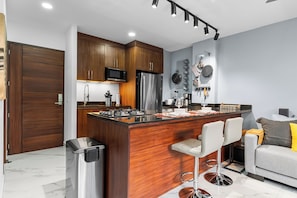 A modern kitchen with wooden cabinets, stainless steel appliances, and a central island with bar stools. - Casa Lúmina an Elevated Escape in Puerto Vallarta (Puerto Vallarta)