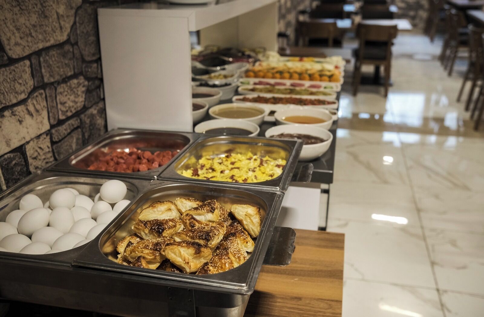 Un buffet proposant une variété de plats, notamment des œufs, de la viande et des pâtisseries.