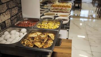 Un buffet proposant une variété de plats, notamment des œufs, de la viande et des pâtisseries.