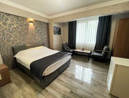 Habitación de hotel con cama, escritorio, dos sillas, armario y un cuadro en la pared.