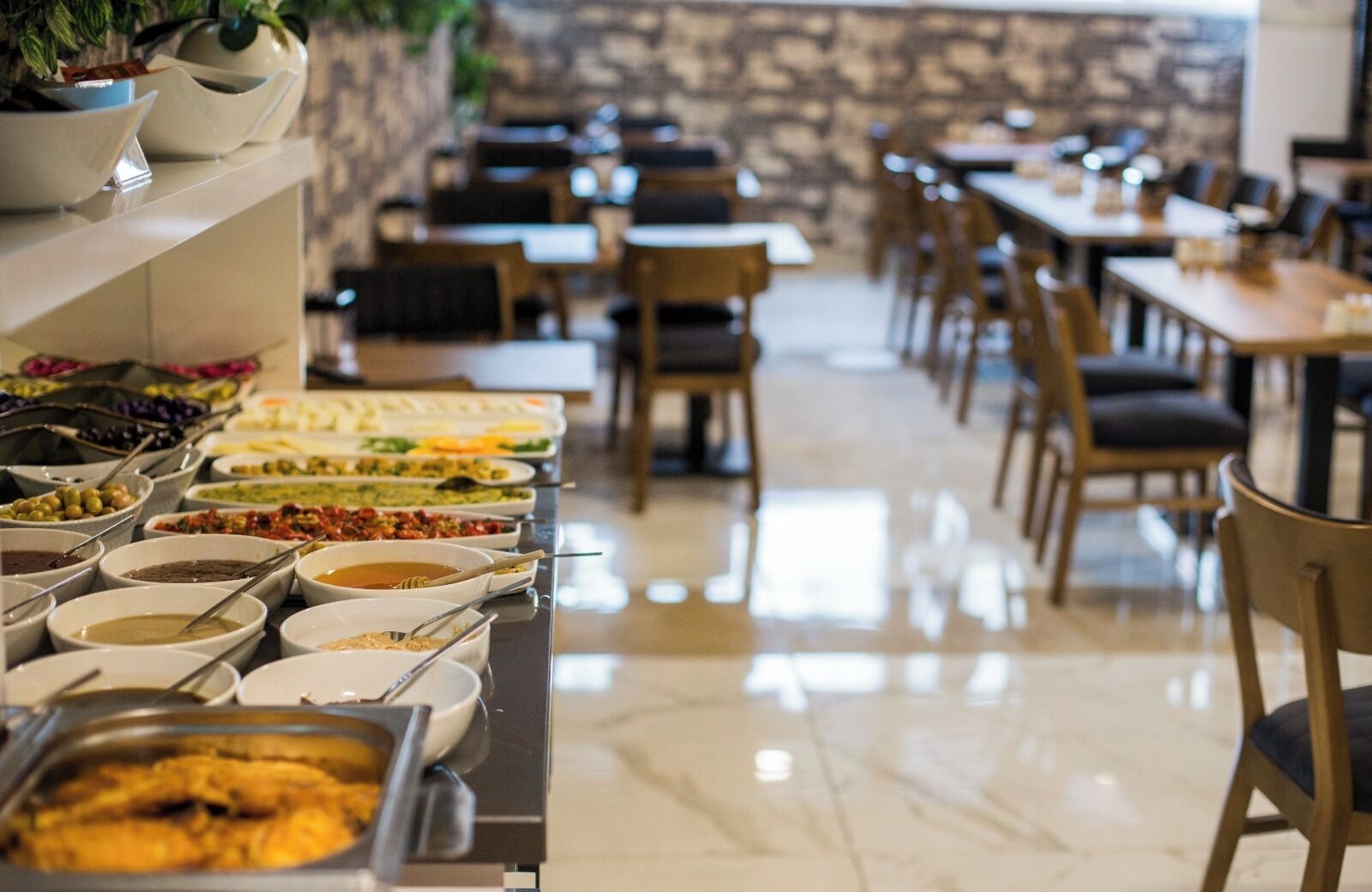 A buffet setup with various food items and a stone wall in the background.