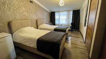 Une chambre d’hôtel avec deux lits, un petit bureau, une armoire et une fenêtre avec des rideaux.