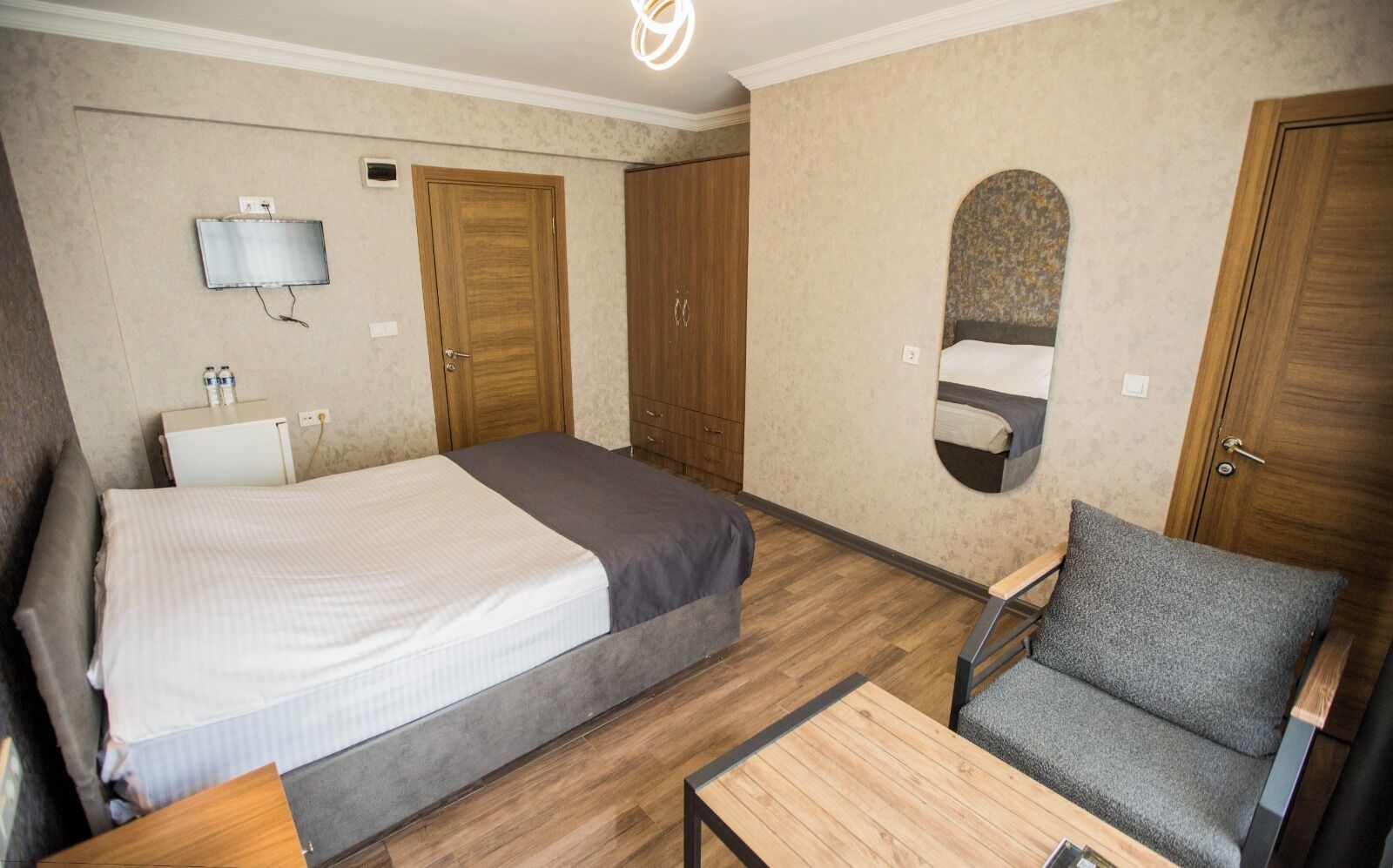 Une chambre d’hôtel équipée d’un lit, d’un bureau, d’une chaise, d’un miroir et d’une armoire.