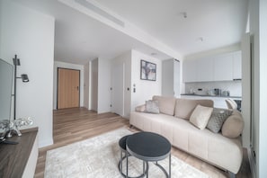 Eine moderne Wohnung mit Wohnzimmer, einer Küchenzeile und einem Flur, der zu einer Tür führt.