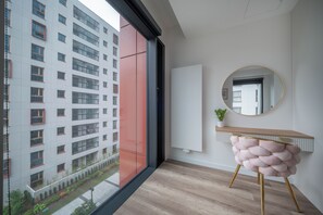 Ein modernes Interieur mit einem großen Fenster, einem runden Spiegel und einer kleinen Pflanze auf einer Konsole.
