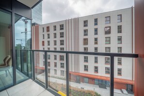 Ein modernes Gebäude mit Glasfassade, zahlreichen Fenstern und einem Balkon mit Metallgeländer.