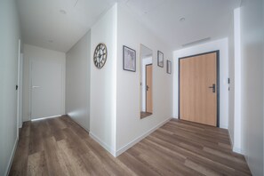 Ein Flur mit Holzboden, weißen Wänden und einer Holztür am Ende.