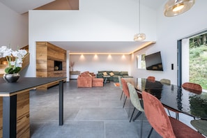 A modern interior with a dining area, sofas, and a large window. - L'Écrin des Noyers - Vue montagne, proche forêt (La Bâthie)