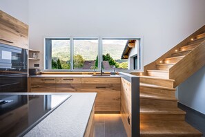 Eine moderne Küche mit großem Fenster, Holzschränken und einem eingebauten Backofen.