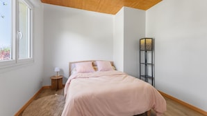 A bedroom with a bed, a bedside table, a lamp, a rug, and a floor lamp. - Le Buquet - Jardin clos de 700 m² (Elbeuf)