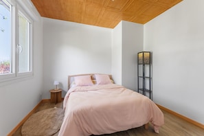 Um quarto com cama, mesa de cabeceira, abajur, tapete e luminária de chão.