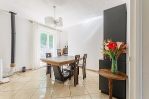 Cozinha moderna com mesa de jantar, cadeiras, um armário preto e um vaso com flores.