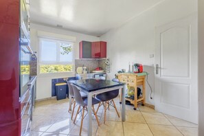 A compact kitchen with a dining table, chairs, and a small cabinet. - Le Buquet - Jardin clos de 700 m² (Elbeuf)
