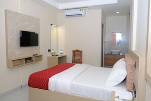 A hotel room with a bed, a television mounted on the wall, a bedside table with a remote control, a mirror, and a bathroom with a sink and mirror. - Highway Suites Kochi (Kochi)