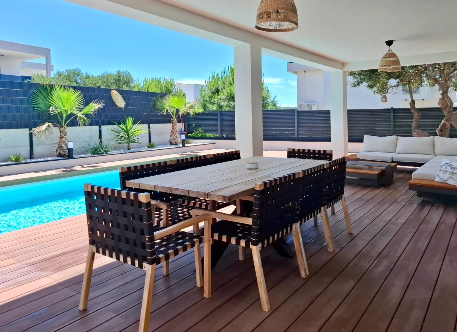 An outdoor patio with a pool, wooden deck, and seating area.