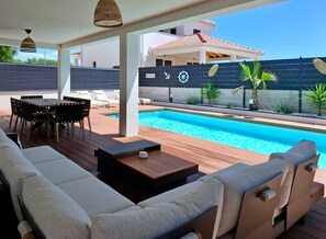 A poolside area with a wooden deck, outdoor seating, and a pool.