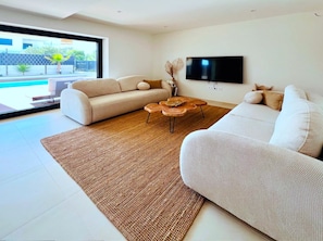 A modern living room with a sofa, a coffee table, and a flat-screen TV mounted on the wall.