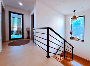 A modern interior with a staircase, a large window, and a view of the outdoors. - Vila Esnella – Private Pool & Panoramic Sea View (Primošten)